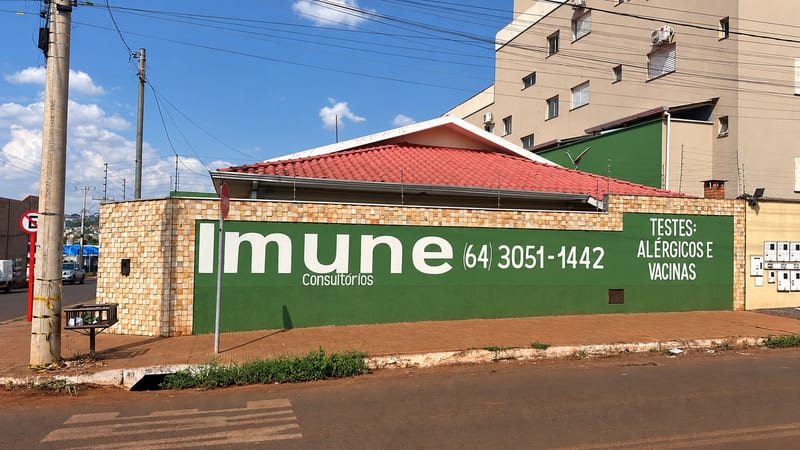 Muro lateral do consultório Imune Consultórios com o telefone (64) 3051-1442 e a indicação de testes alérgicos e vacinas, no Setor Morada do Sol, Rio Verde